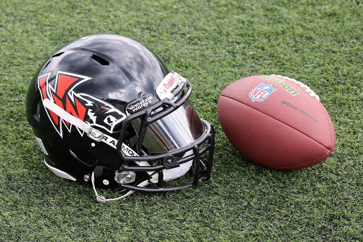 A helmet on its own, chin strap loose, facemask bars catching the light.